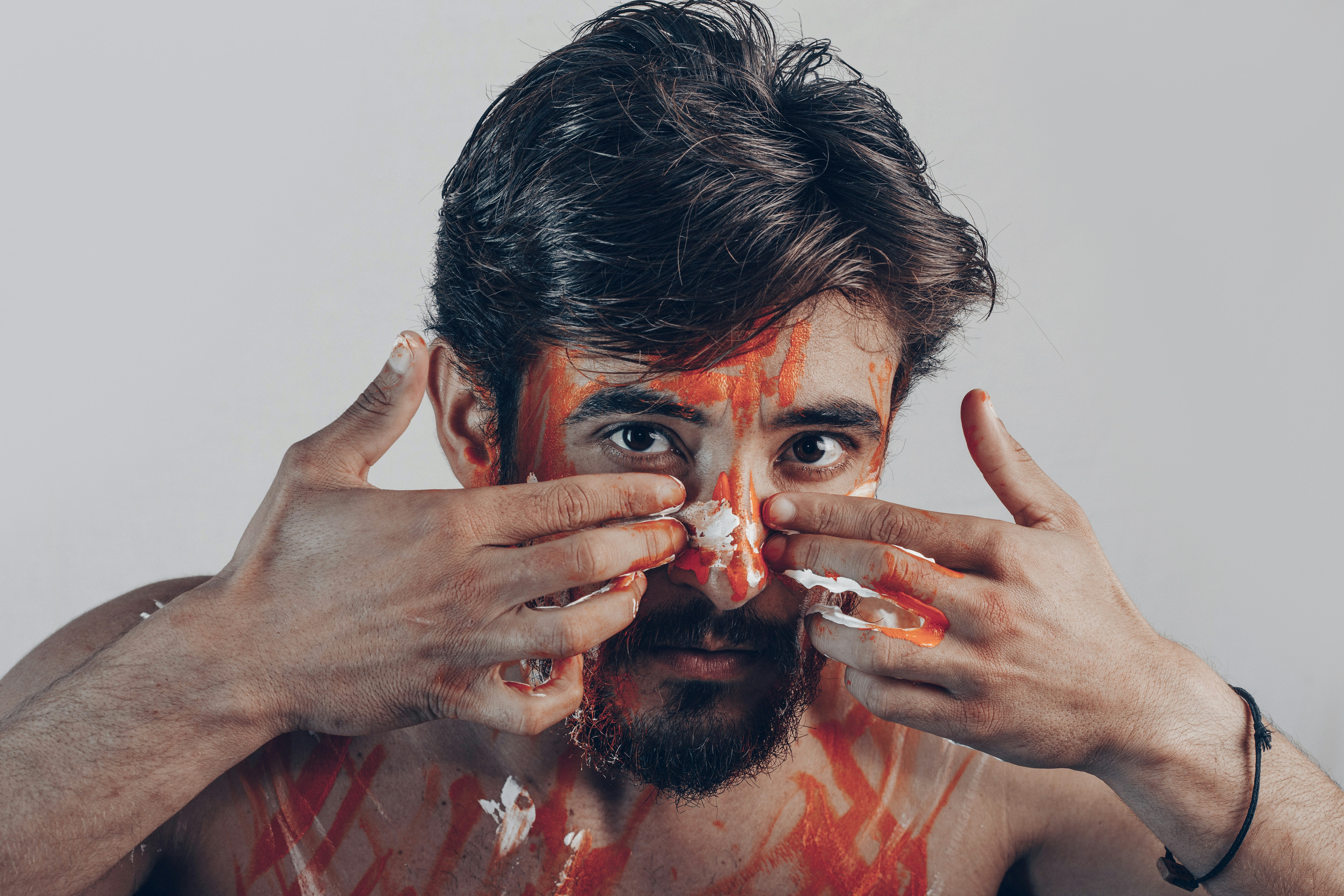 man in red crew neck shirt covering his face with hands